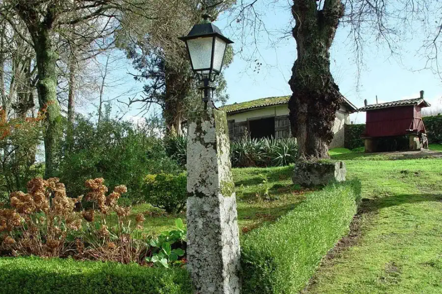 Jardin avec lanterne en pierre, dépendances et hórreo galicien à l’arrière-plan.